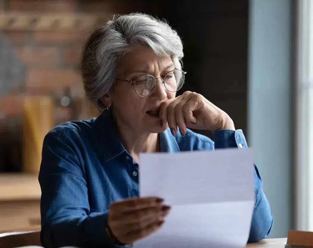 Concerned woman sitting at a desk looking over paperwork